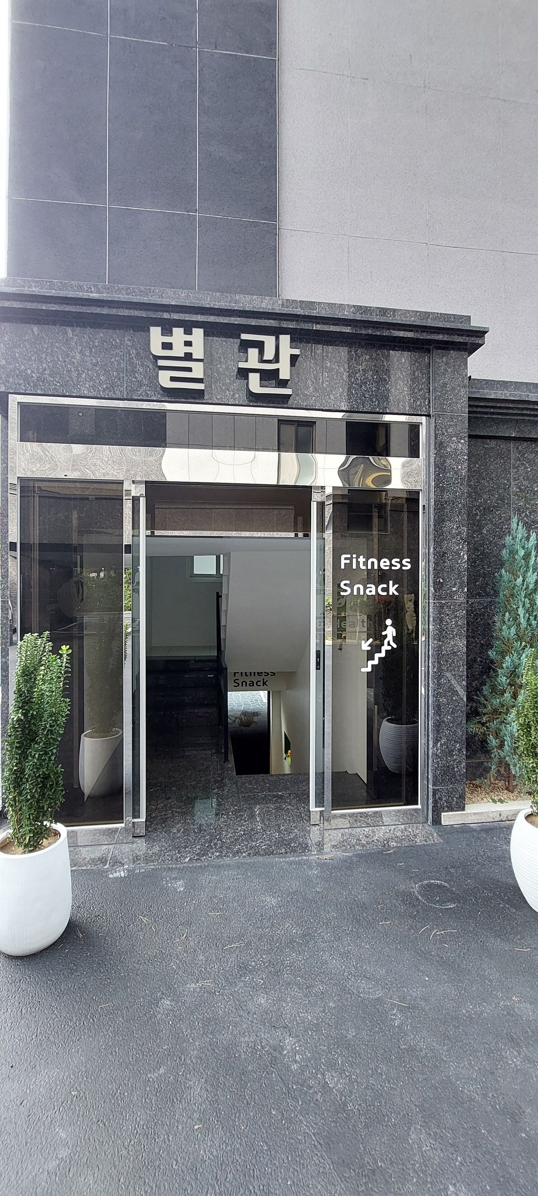 A building entrance with a sign reading "Fitness Snack" and a staircase leading inside.