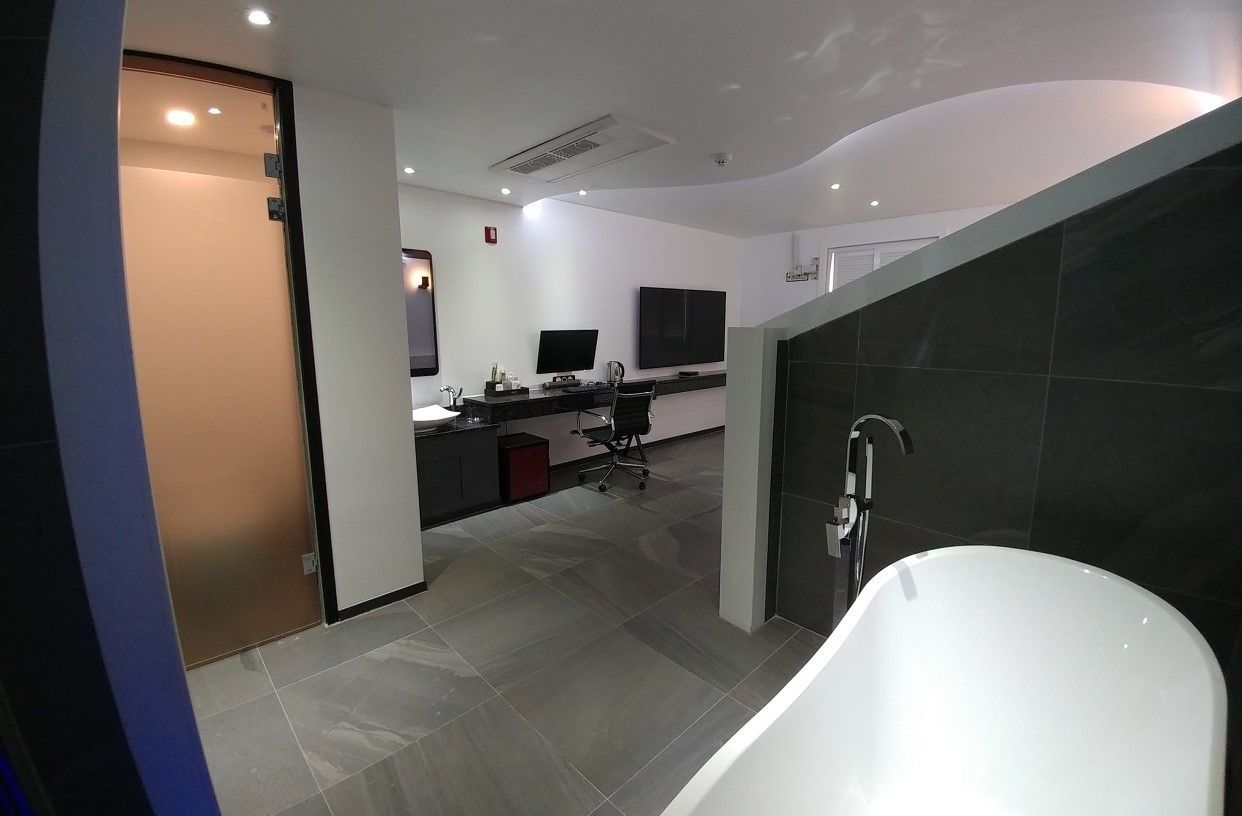 Un baño moderno con una bañera blanca, un escritorio con un ordenador y un televisor de pantalla plana.