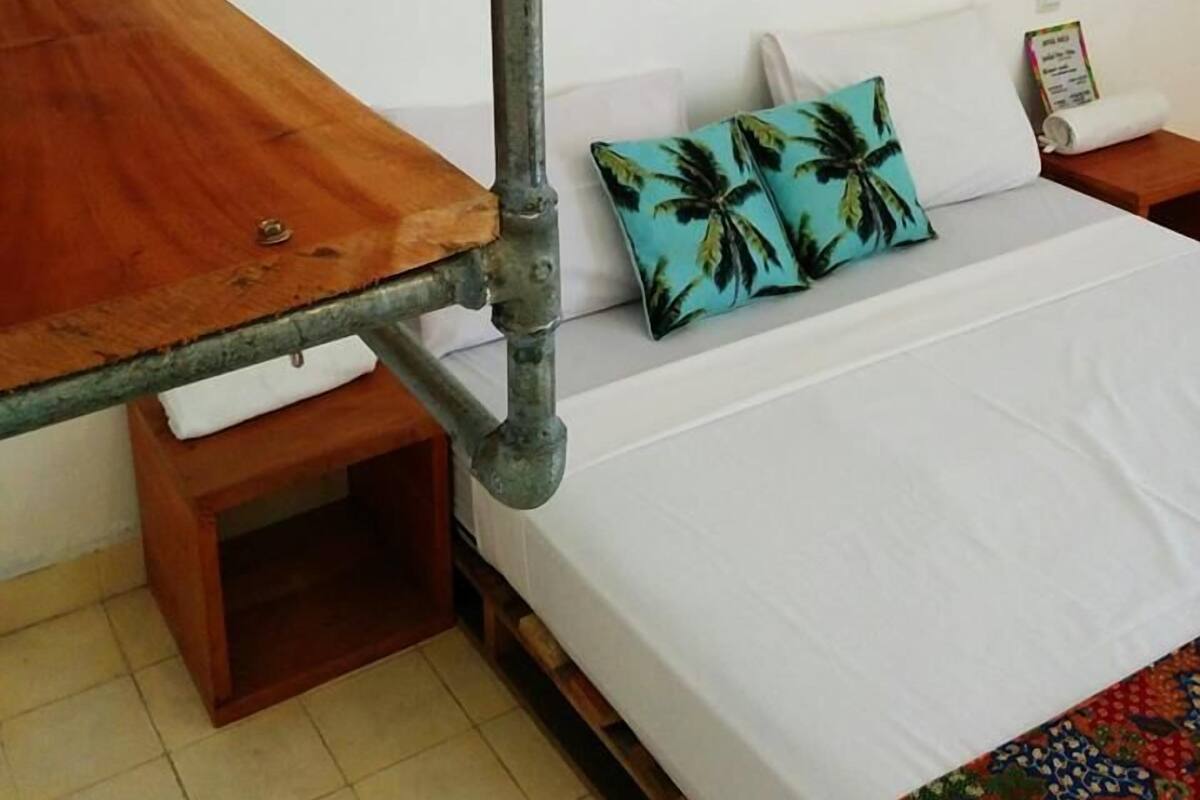 Um quarto com uma cama, uma mesa de madeira e duas luminárias fixadas na parede.