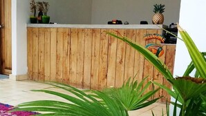 Un área de recepción con un mostrador de madera, un letrero que dice 'Welcome' y una decoración de piña.