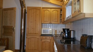 Una cocina con armarios de madera, una campana extractora de acero inoxidable, un microondas, una cafetera y un tostador.