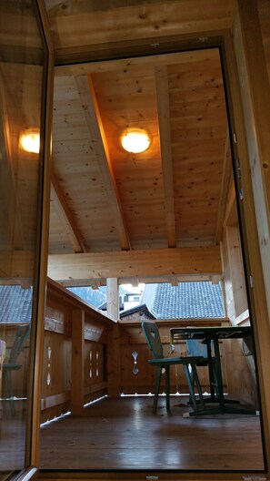 A wooden interior with a high ceiling, a round ceiling light, and a view of the outside through a glass door. - Tiroler Chalet Oetztal (Sautens)