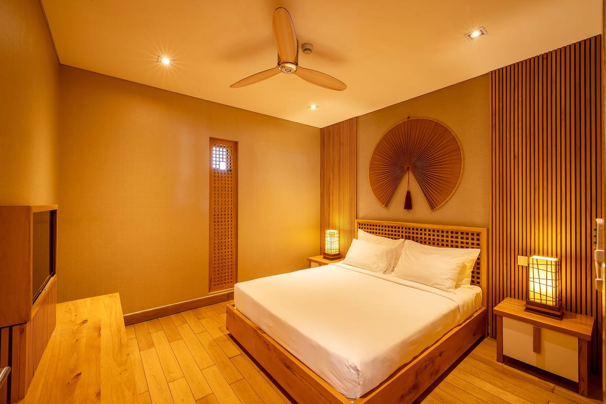 Ein Schlafzimmer mit einem hölzernen Bett, einem Deckenventilator und einem runden Wanddekor.