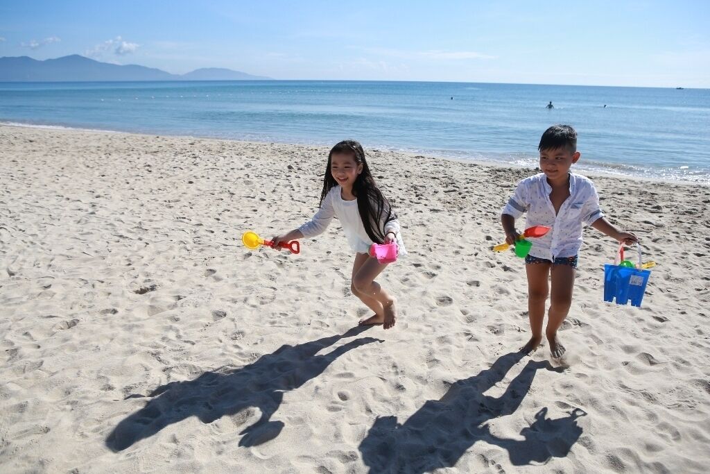 Na praia, areia branca, espreguiçadeiras, guarda-sóis 
