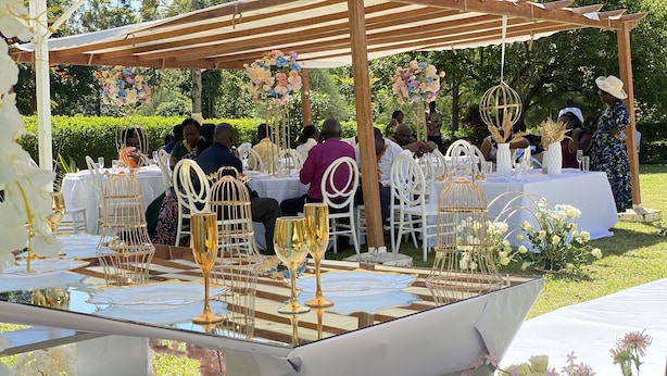 An outdoor event with tables set for guests, featuring white tablecloths and gold decorative elements. - Babblers Park (Migori)