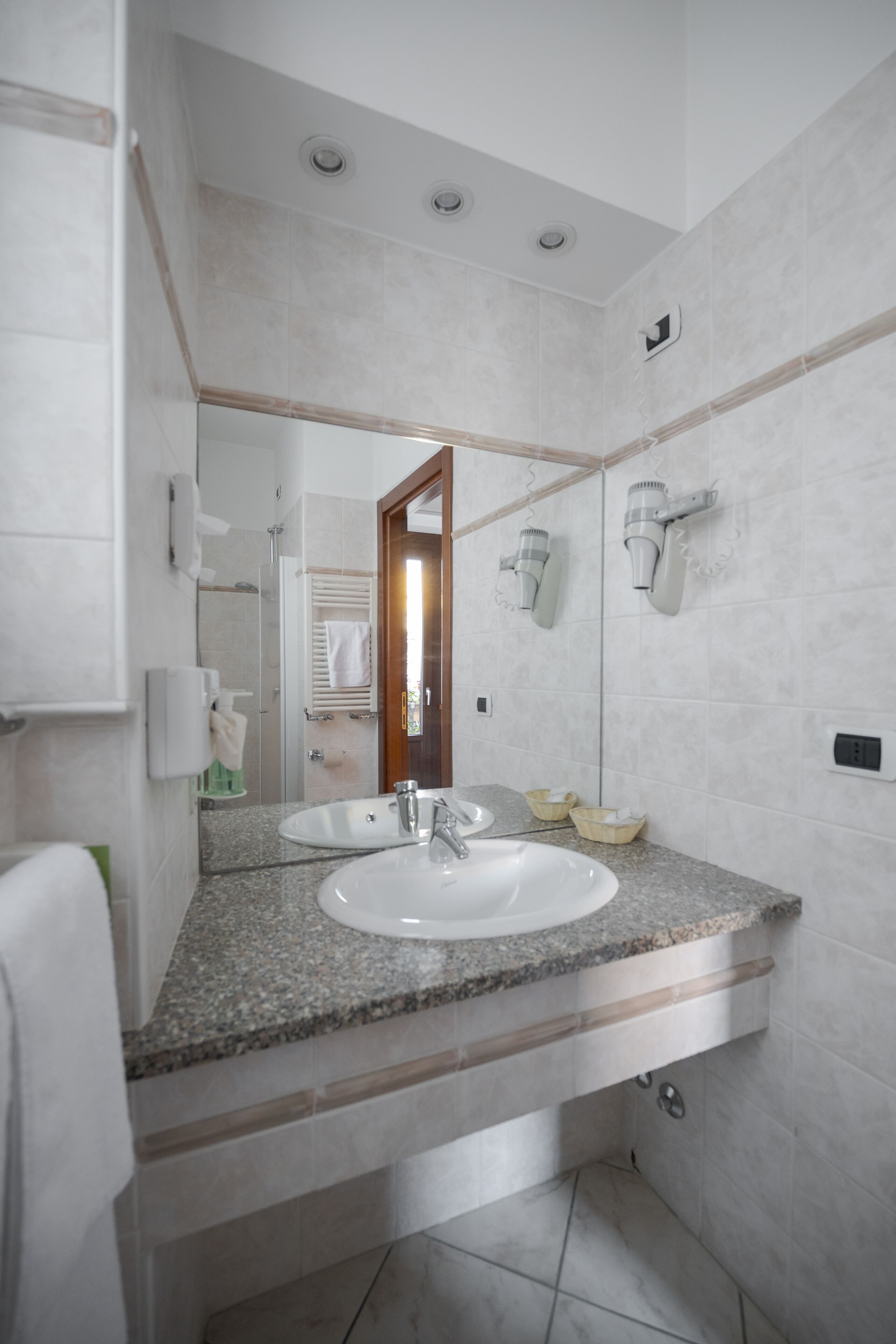 A bathroom with a granite countertop, a white sink, a mirror, and a towel rack.