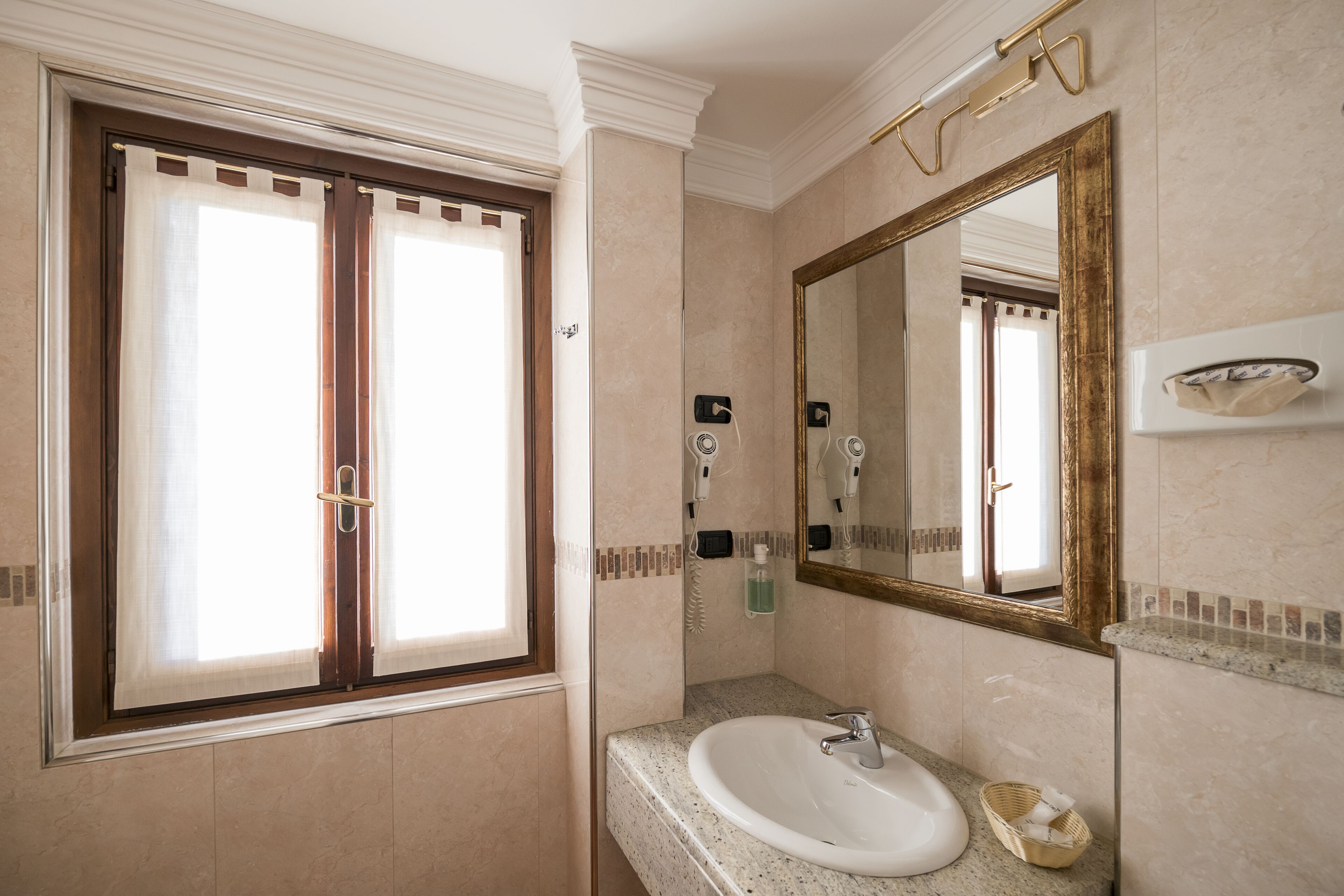 A bathroom with a large window, a sink, a mirror, and a towel rack.