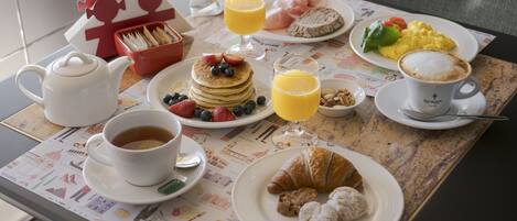 A breakfast table with a croissant, coffee, juice, and a plate of scrambled eggs and toast.