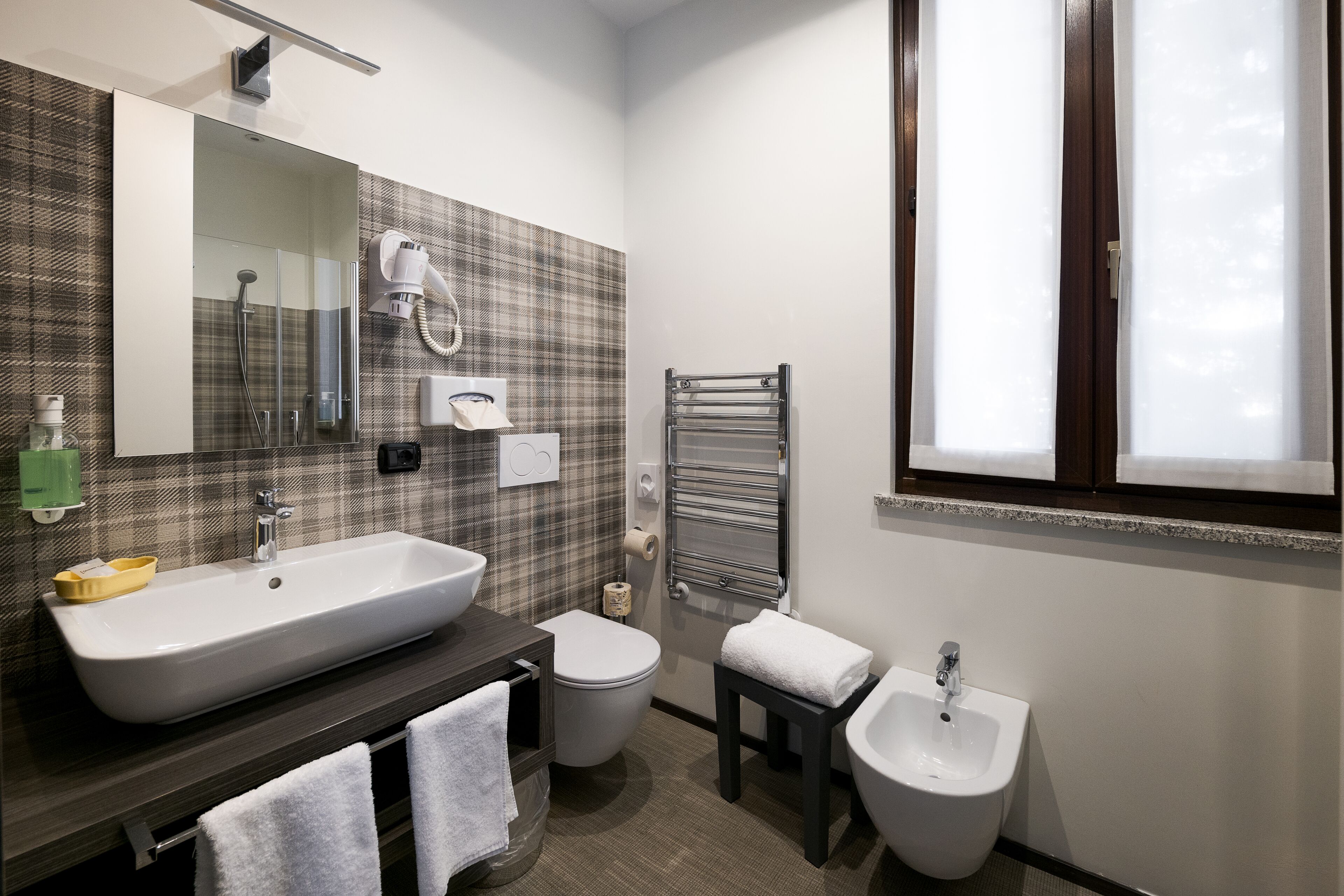 Un baño moderno con un lavamanos grande, inodoro, bidé y un perchero para toallas.