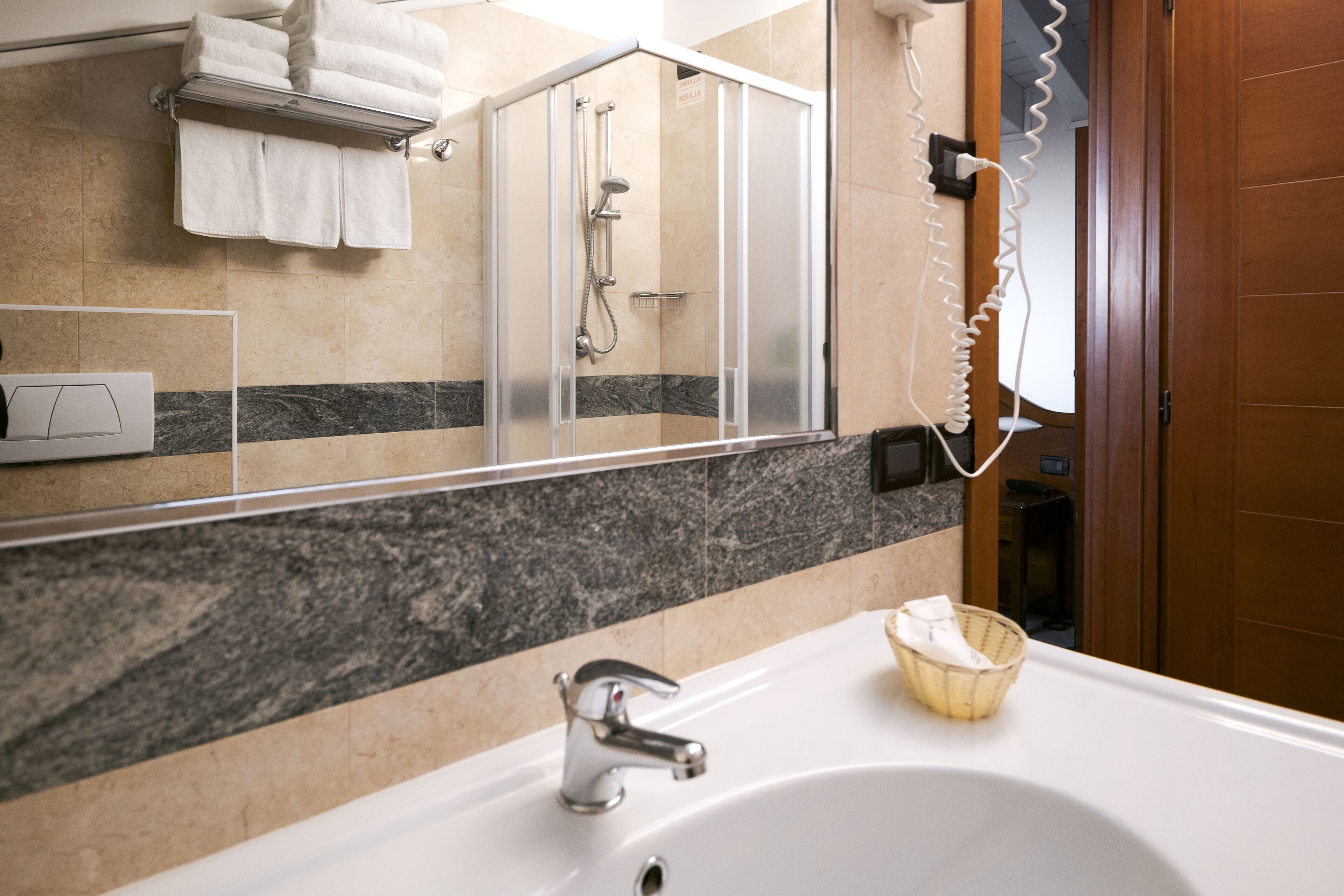 A bathroom with a white sink, a mirror, a shower enclosure, and a towel rack.