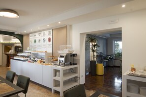 A modern cafe with a central counter, seating area, and a view of the adjacent kitchen. - Hotel Ungheria Varese 1946 (Varese)