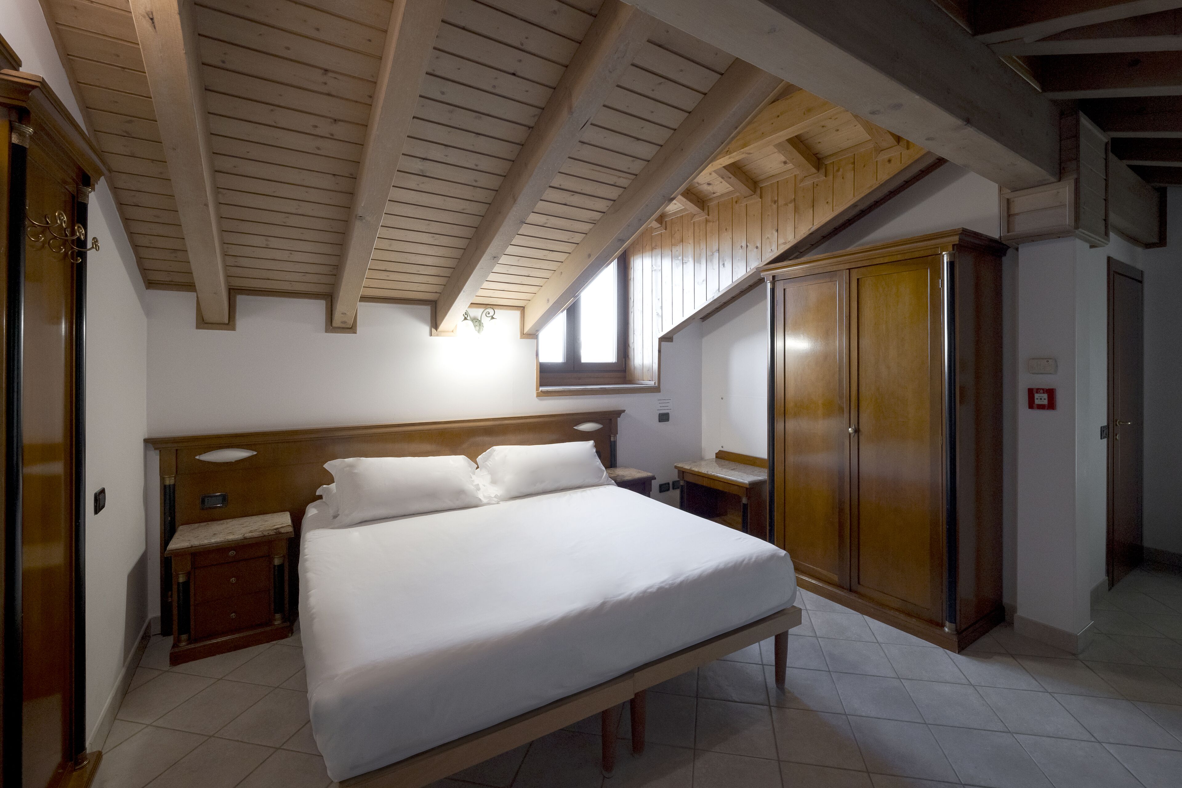 Un dormitorio con una cama grande, cabecera de madera, un armario y una mesita de noche pequeña.