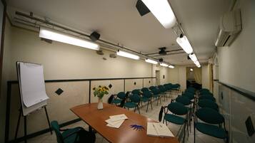 A conference room with a long table, chairs, a whiteboard, and a vase with flowers.