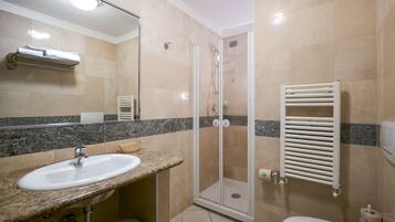 Un baño con lavamanos, espejo, ducha e inodoro.