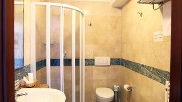 A bathroom with a shower enclosure, a toilet, a bidet, and a sink.