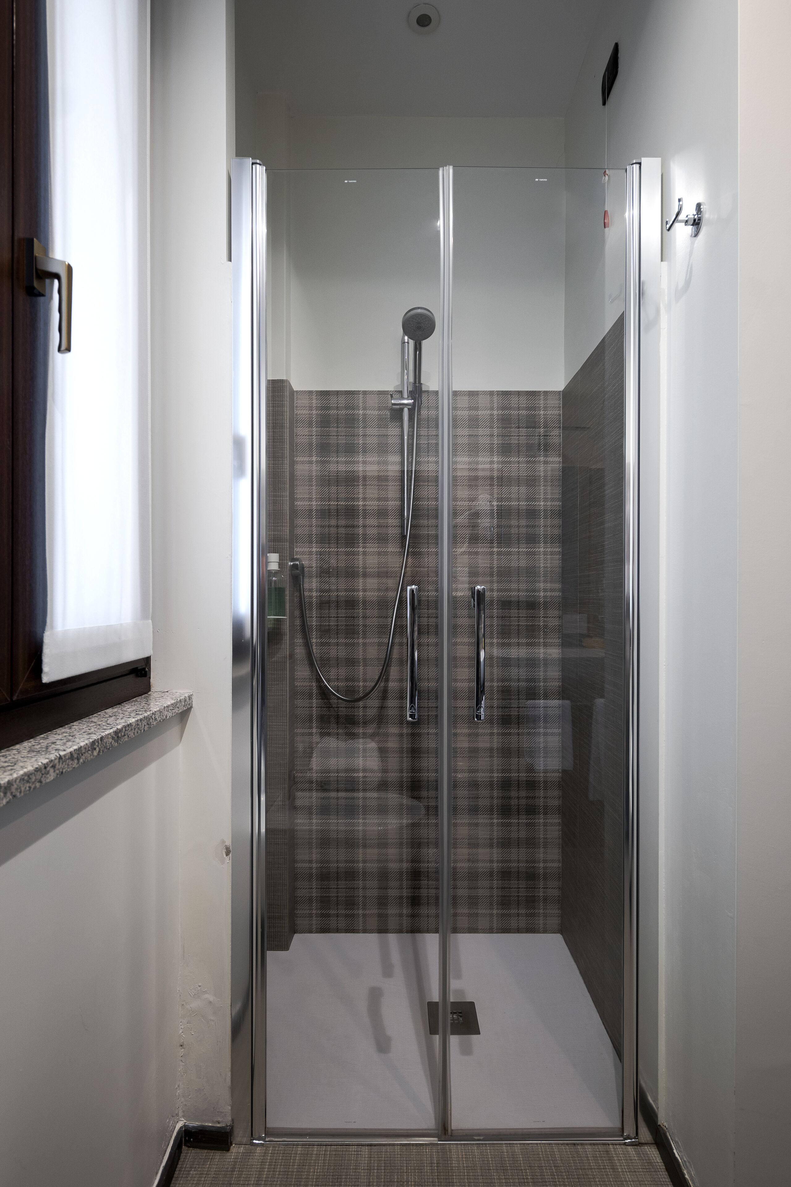 Una ducha moderna con puerta de vidrio, un cabezal de ducha y un panel de control.
