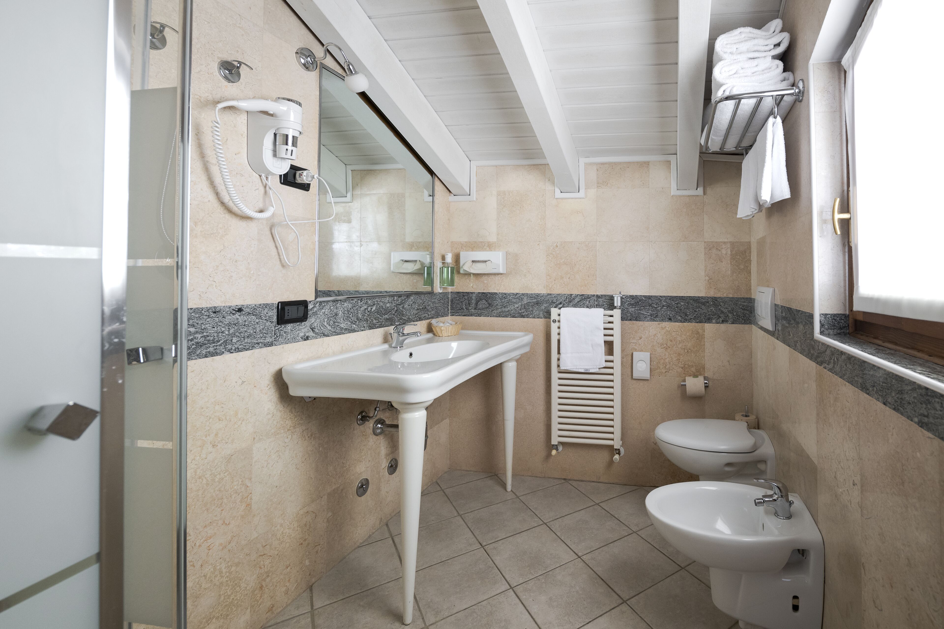 A bathroom with a sink, toilet, bidet, and a glass shower enclosure.