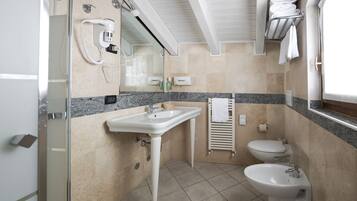 A bathroom with a sink, toilet, bidet, and a glass shower enclosure.