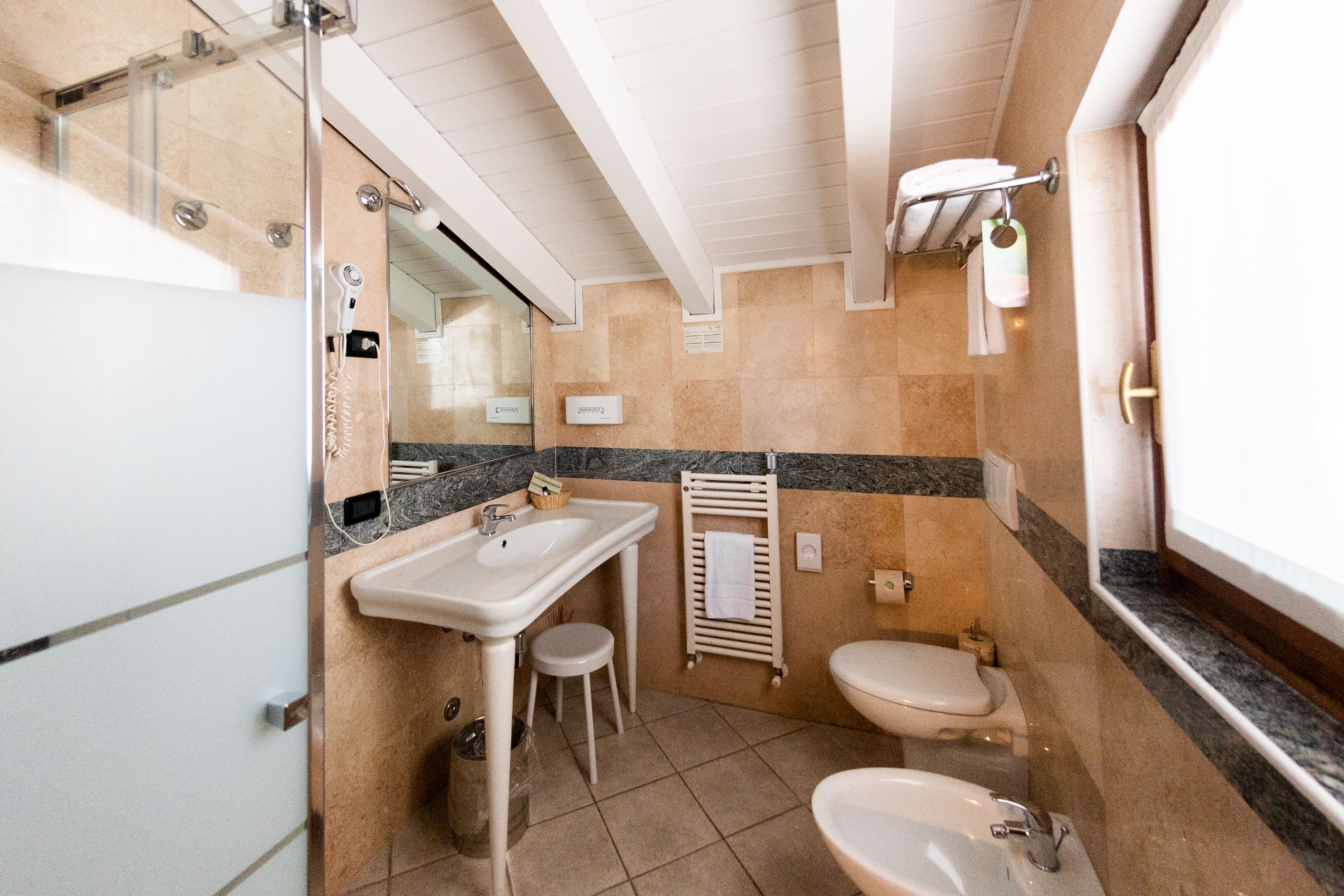 Ein Badezimmer mit Waschbecken, Toilette und Dusche. Handtuchhalter und Spiegel sind vorhanden.