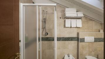 Une salle de bain d’hôtel avec une douche à parois de verre, un lavabo, des toilettes et un porte-serviettes avec des serviettes pliées.