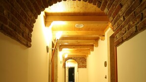 A narrow hallway with a wooden floor, brick walls, and a wooden ceiling. - Hotel Ungheria Varese 1946 (Varese)