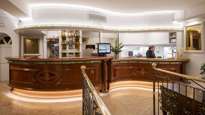 A reception area with a curved wooden desk, a television, and a plant. - Hotel Ungheria Varese 1946 (Varese)