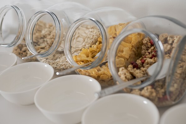 Frascos de vidrio con granola y avena, y tazones blancos.