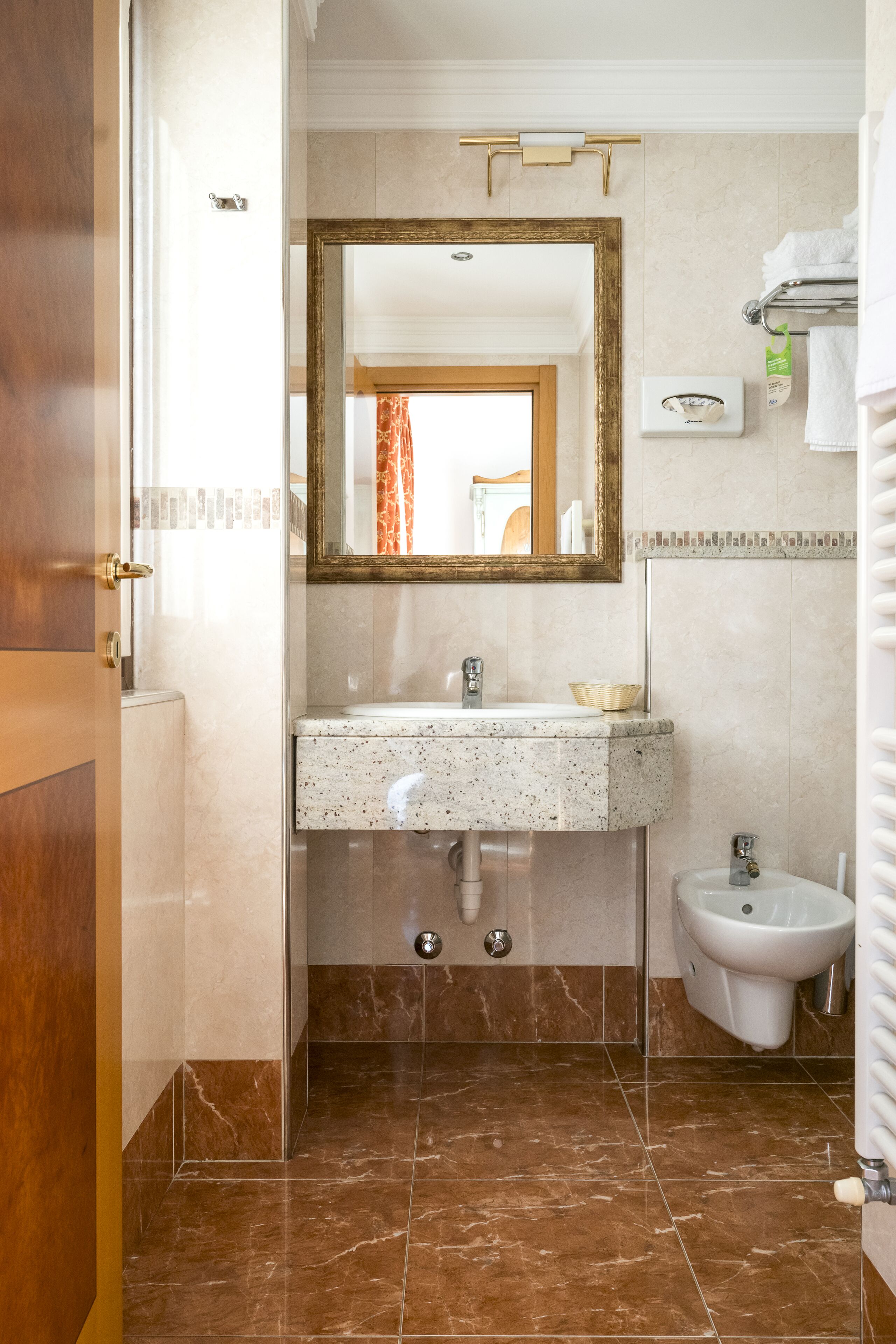 Ein Badezimmer mit Marmorwaschbecken, einem Bidet und einem Spiegel.