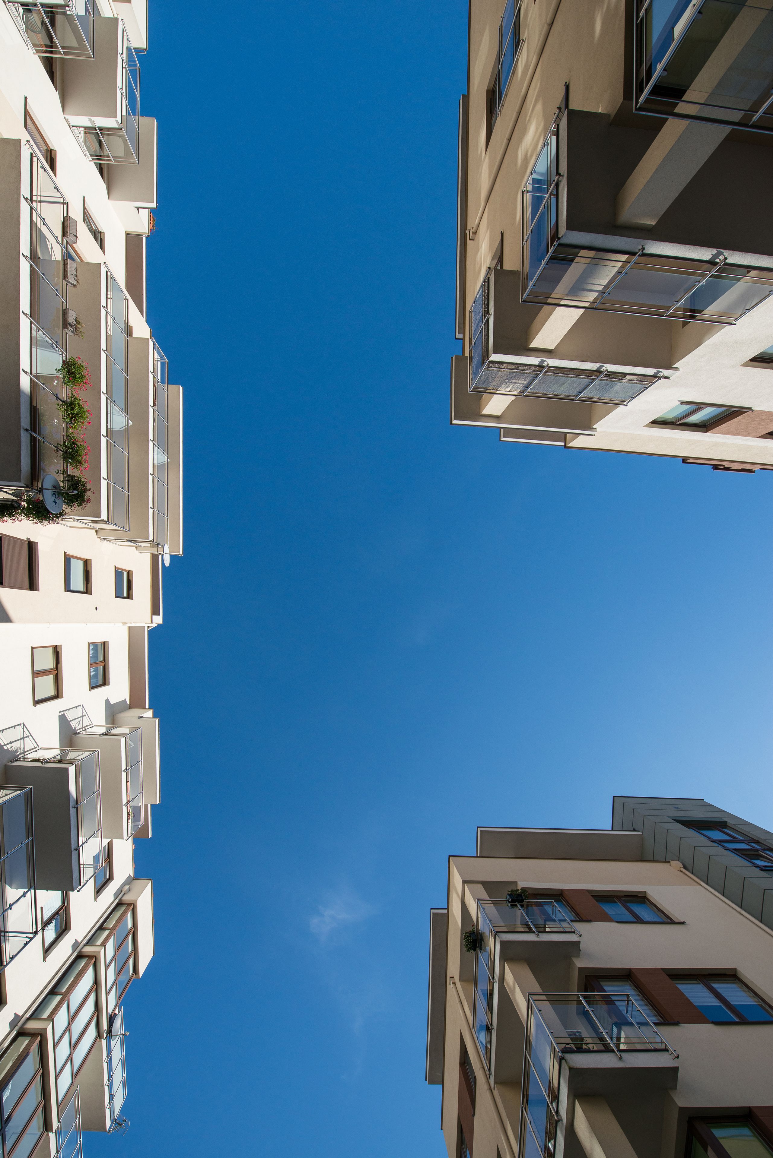 A modern multi-story building with balconies, large windows, and a clear blue sky.