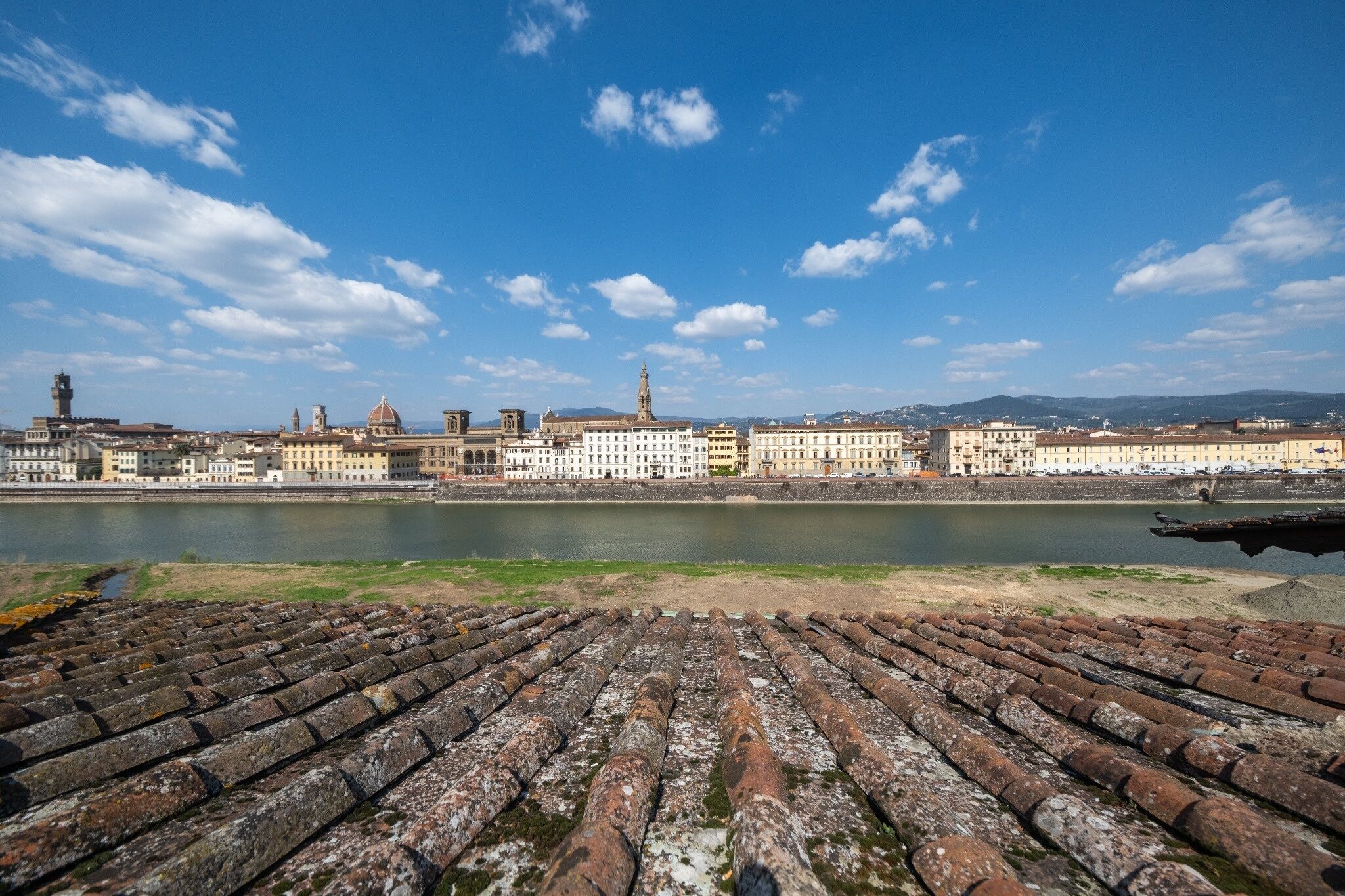 Paisaje urbano frente al río, con edificios históricos y un primer plano de baldosas.