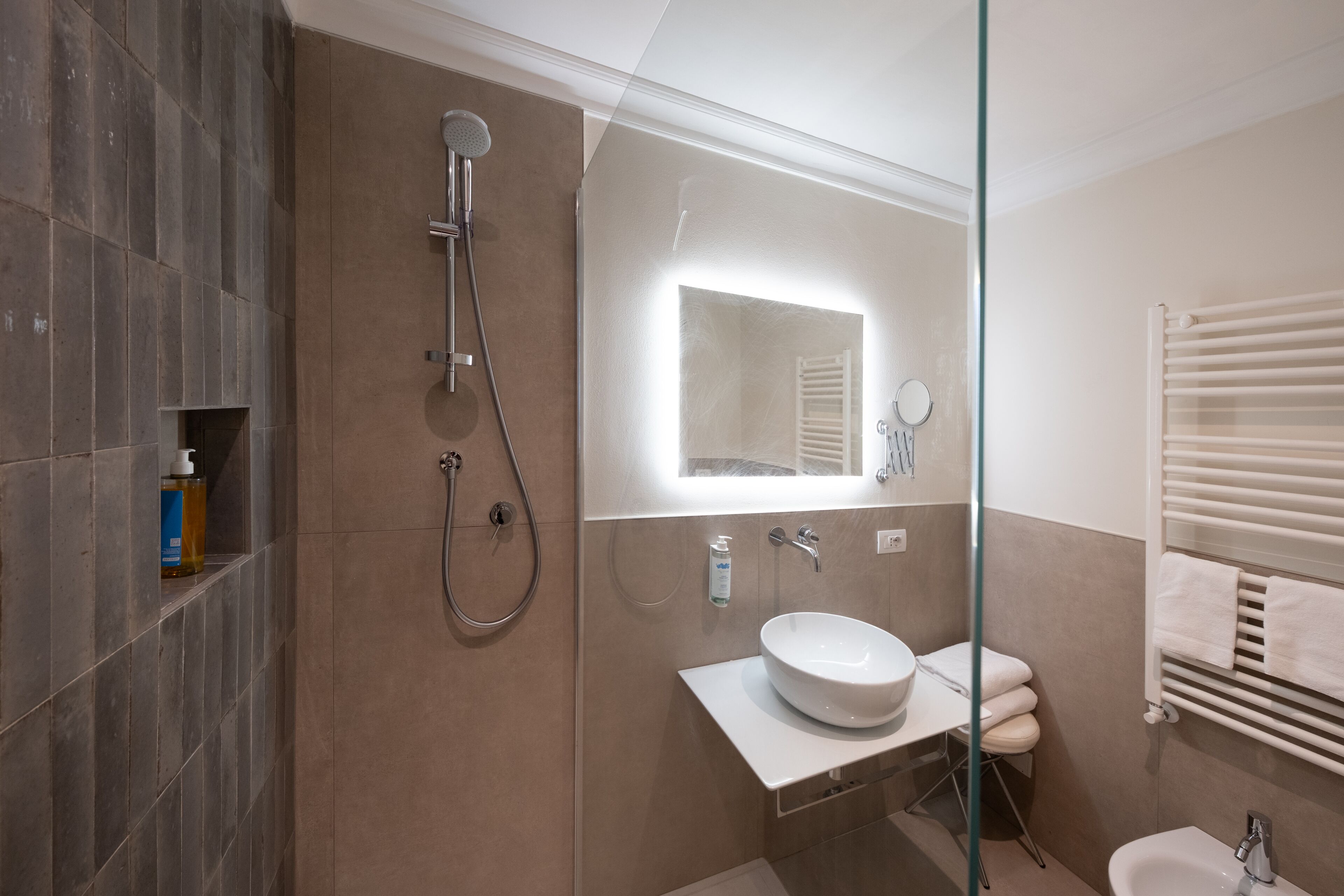 Un baño moderno con cabina de ducha de vidrio, un lavabo blanco y un inodoro.