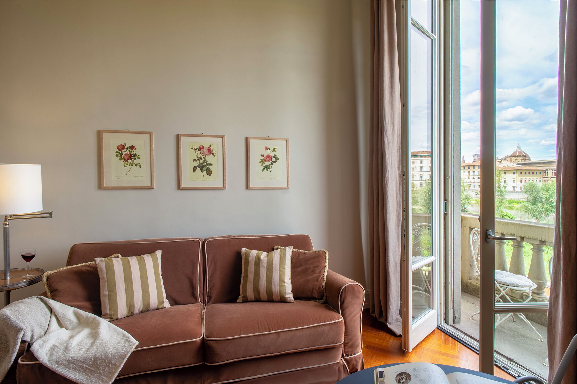 A living room with a brown sofa, striped pillows, and framed botanical prints on the wall.