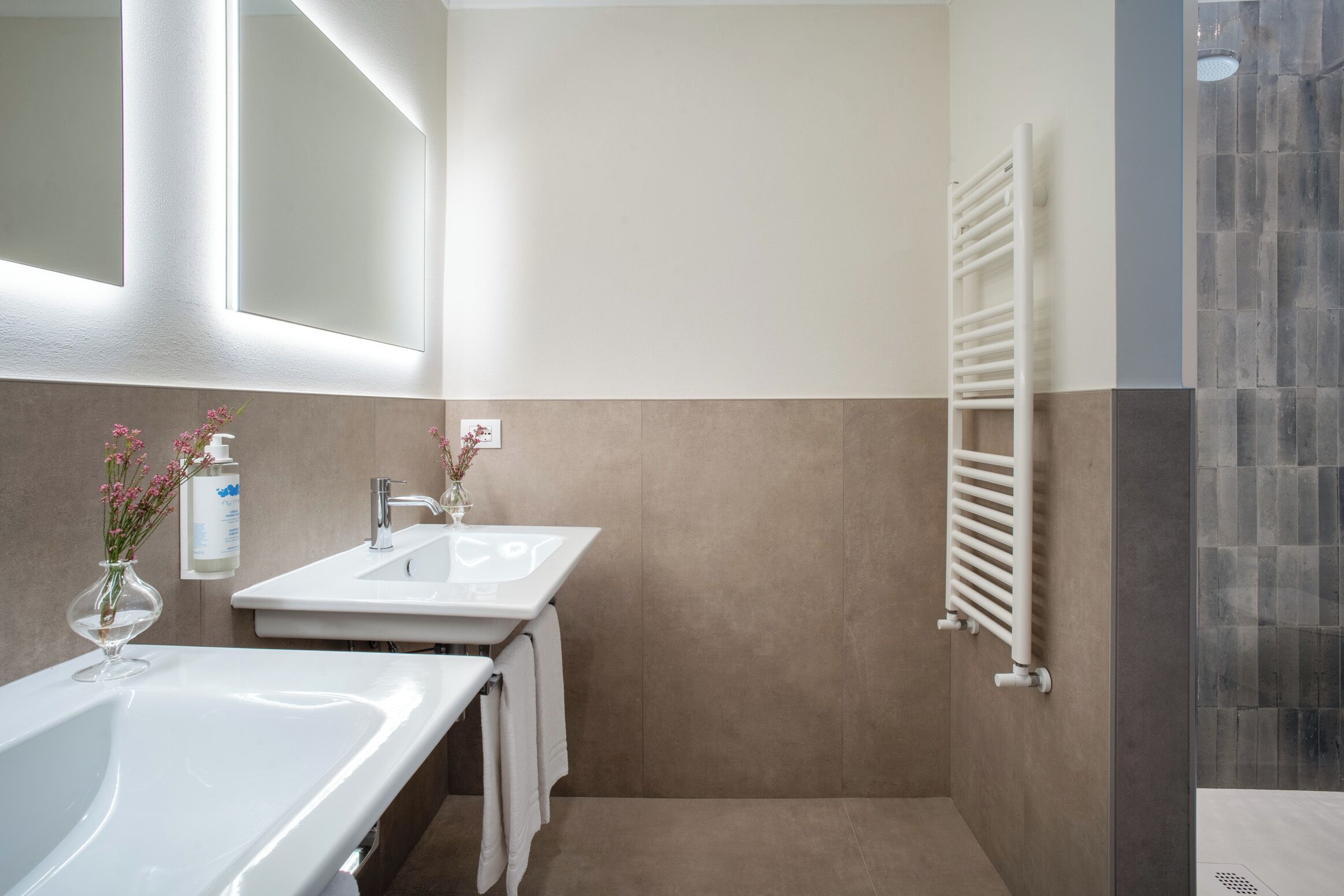 Une salle de bain avec une baignoire, deux lavabos, un porte-serviettes et un espace douche.