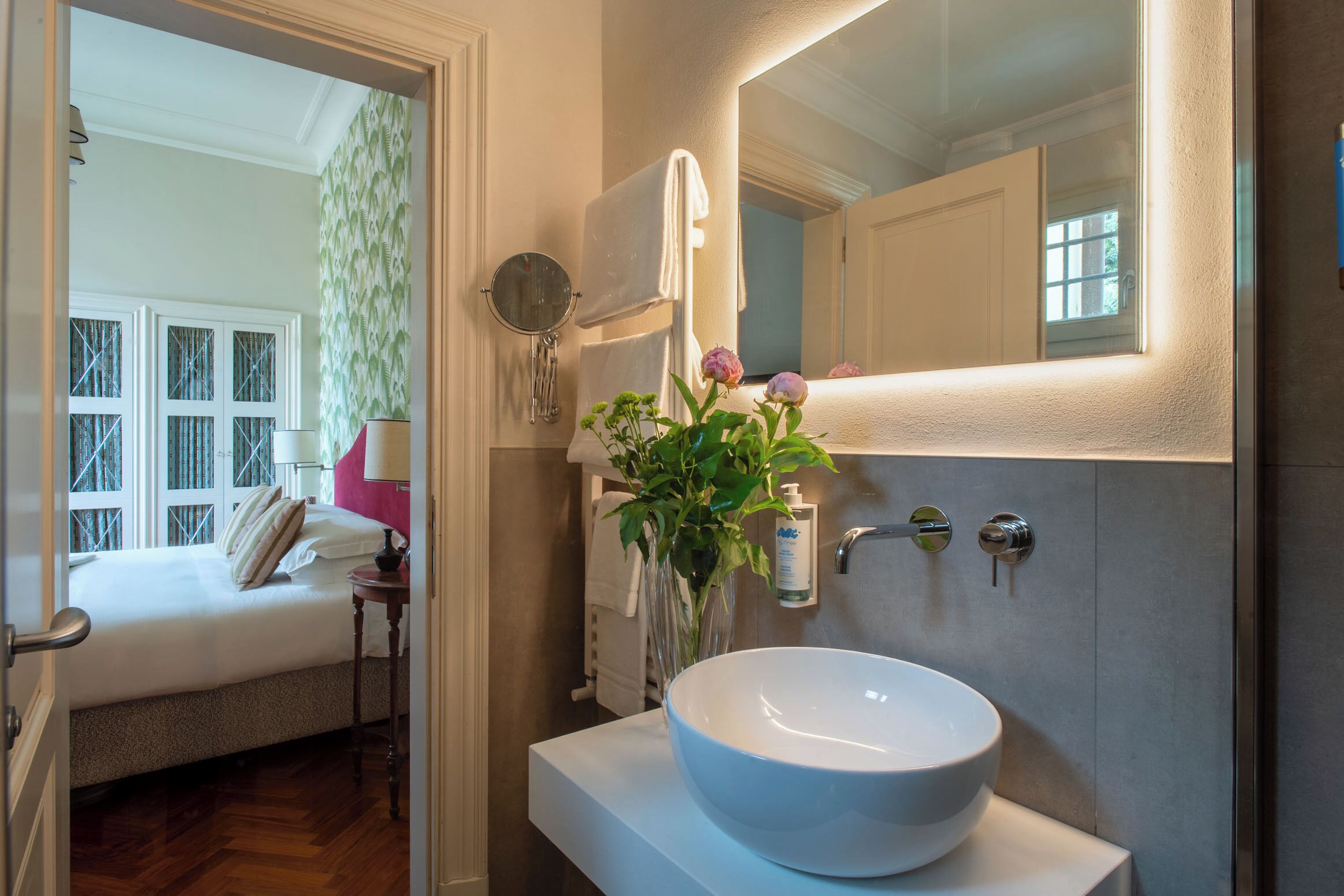 A bathroom with a large white sink, a mirror, and a towel hanging on the wall.