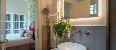 A bathroom with a large white sink, a mirror, and a towel hanging on the wall.