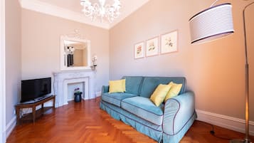 A living room with a sofa, a TV, a fireplace, and framed pictures on the wall.
