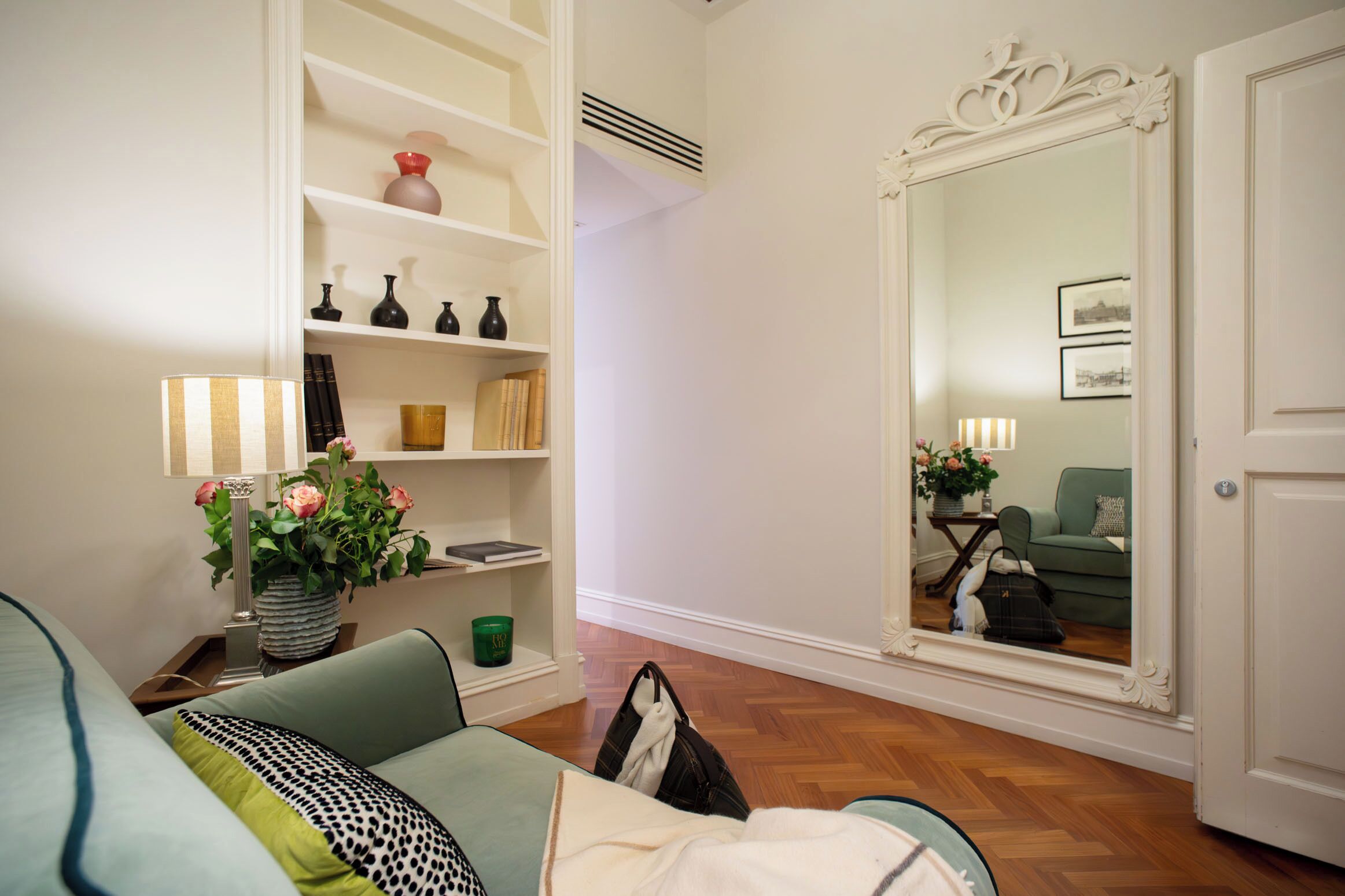 A living room with a sofa, a bookshelf, a mirror, and a green plant.