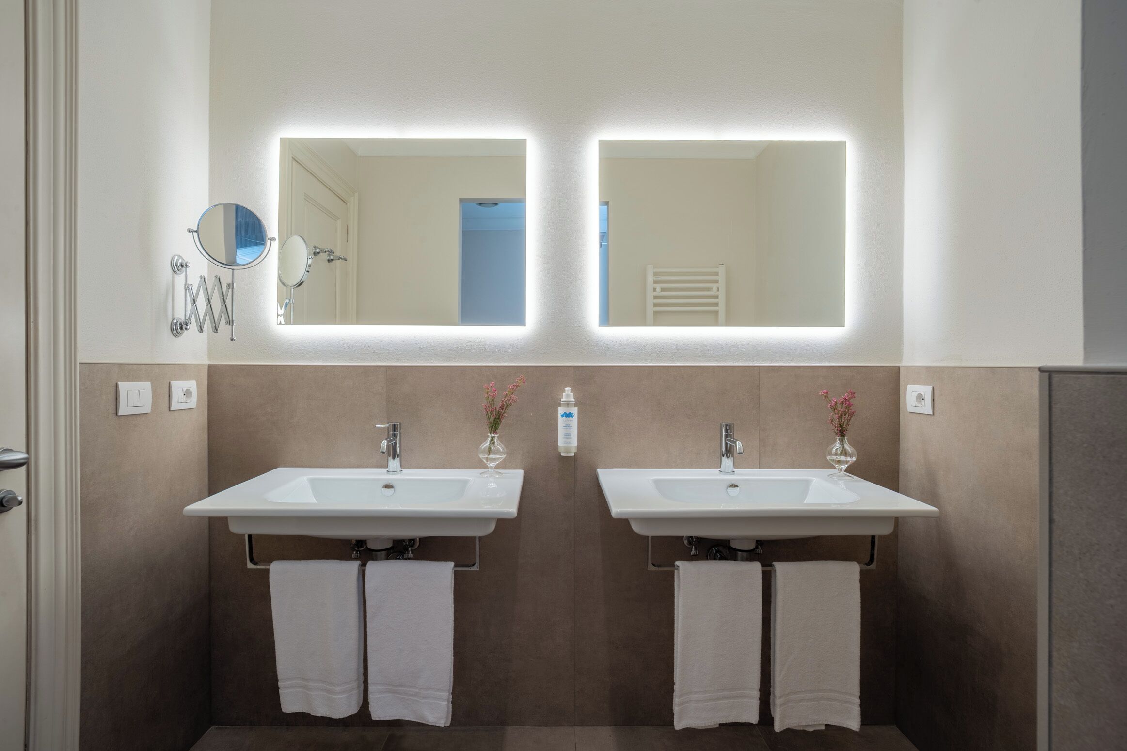 A bathroom with two sinks, a mirror, and a towel rack.