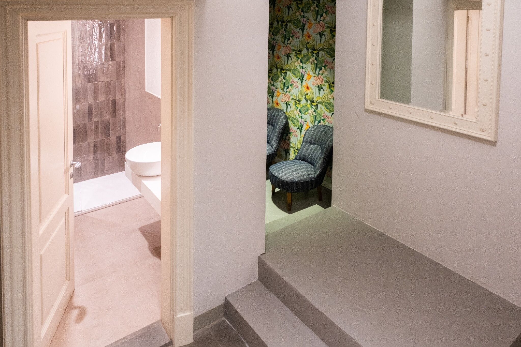 A bathroom with a toilet, shower, and two chairs.