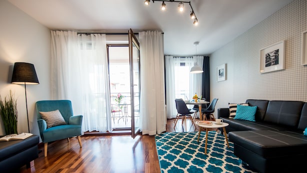 Una sala moderna con un sofá, un sillón y un tapete estampado.