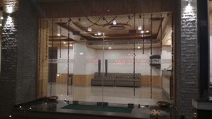 A reception area with a glass partition, a sofa, and a staircase leading to an upper level. - Sarthak Regency (Manali)