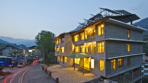 A multi-story building with a ground-level entrance, a balcony, and a solar panel on the roof. - Sarthak Regency (Manali)