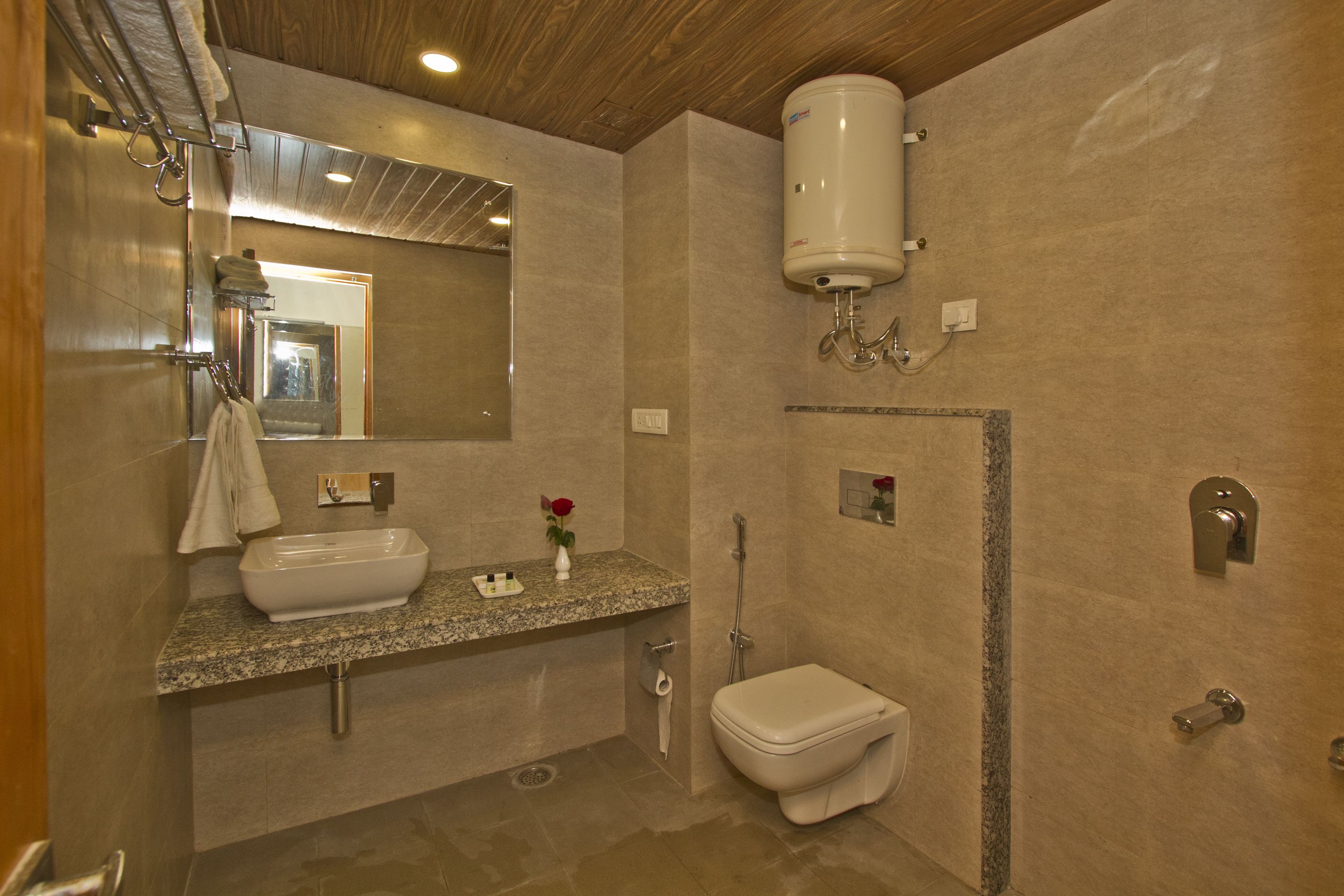 A modern bathroom with a granite countertop sink, a toilet, and a shower.