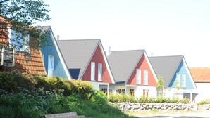 Een rij kleurrijke huizen met schuine daken, een stenen muur en een grindpad.