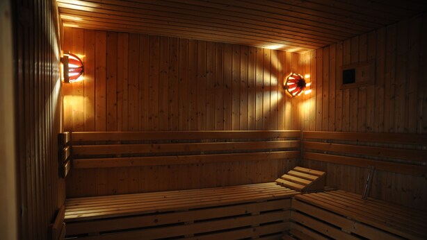 Een sauna met houten banken en twee wandlampen.