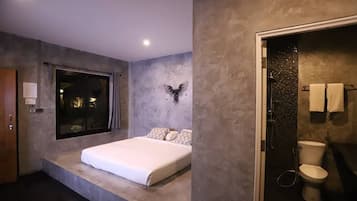 A modern bedroom with a large bed, a window, and a shower area.