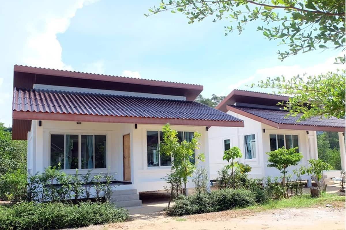 A modern two-story house with a tiled roof, large windows, and a small porch area.