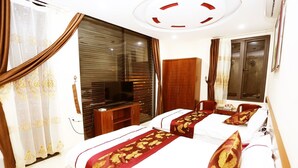 A hotel room with a large bed, a TV, a wardrobe, and a window with curtains. - Tiamo Hotel Ha Giang (Ha Giang 2)