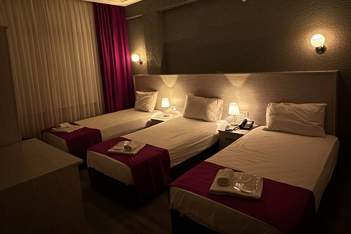 A hotel room with two beds, a desk, and a chair. There are bedside tables with lamps and a telephone.