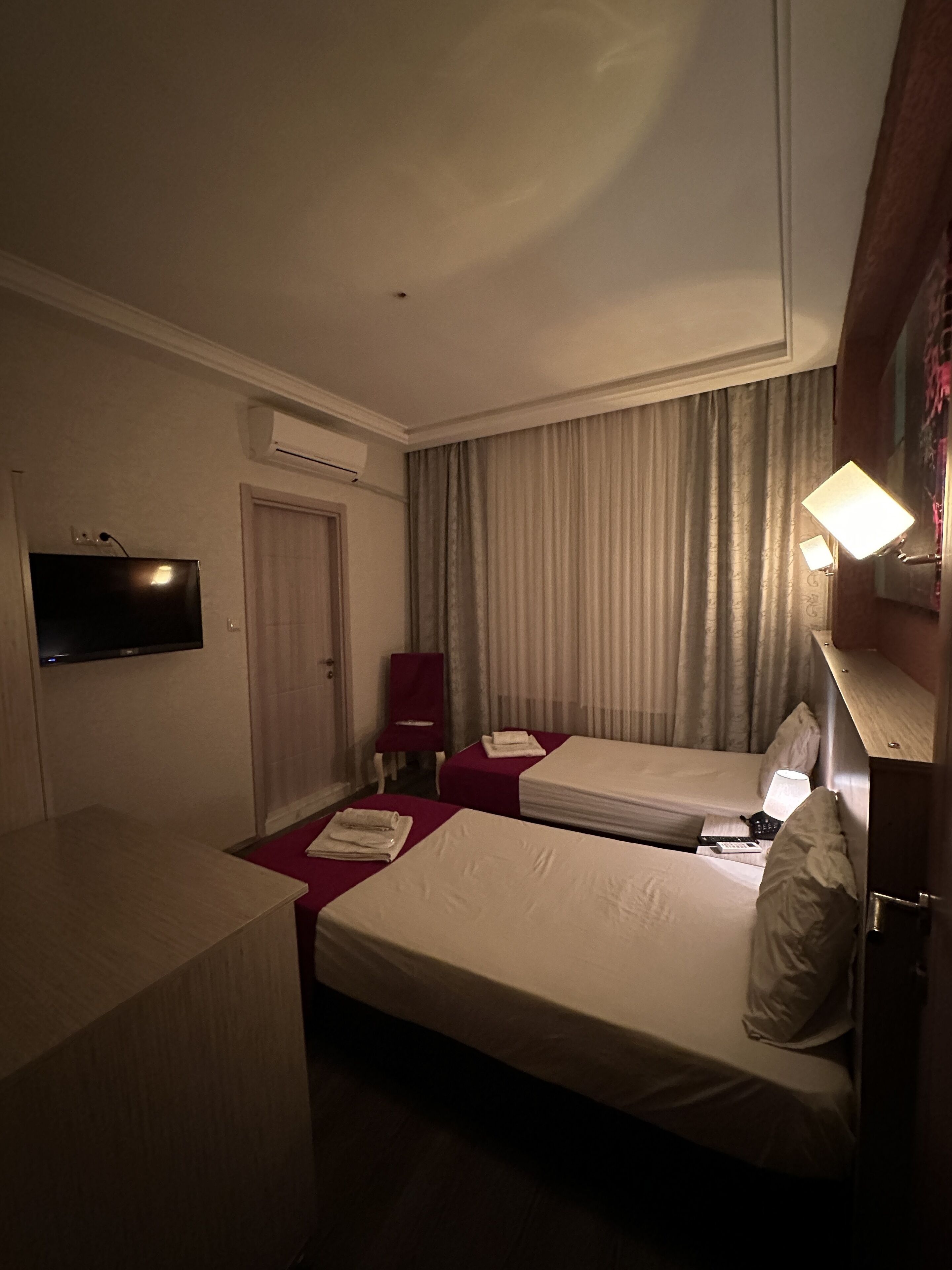Una habitación de hotel con dos camas, televisión, una silla y escritorio.